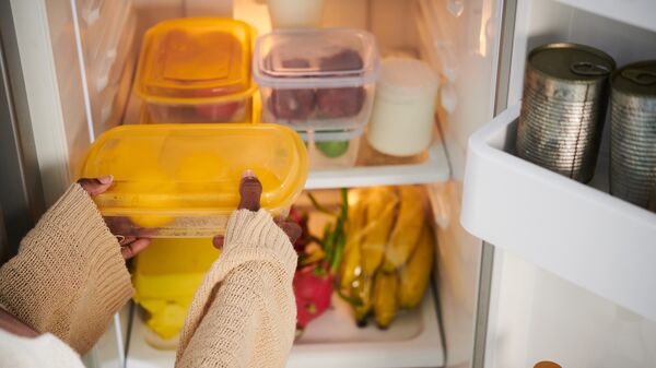 woman putting a plastic container in the fridge