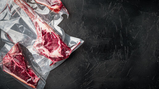 Dry aged steak in a vacuum on black stone background